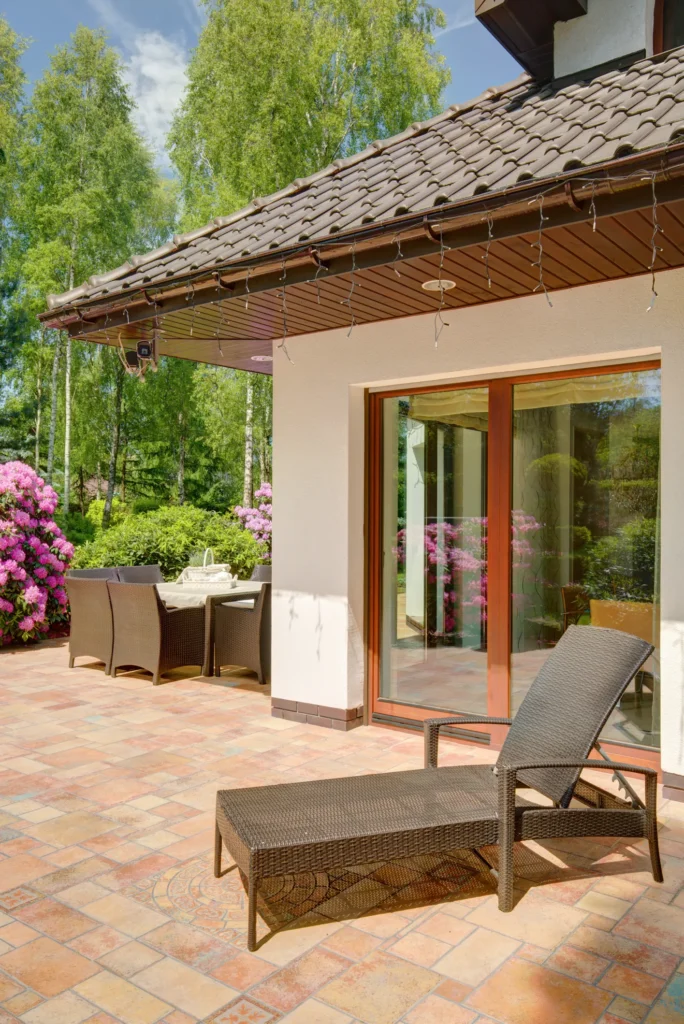 Terrasse mit Terracotta Fliesen vor einem Bungalow mit Liegestuhl